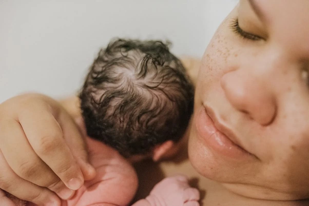 A triumphant first-time mother resting with her newborn